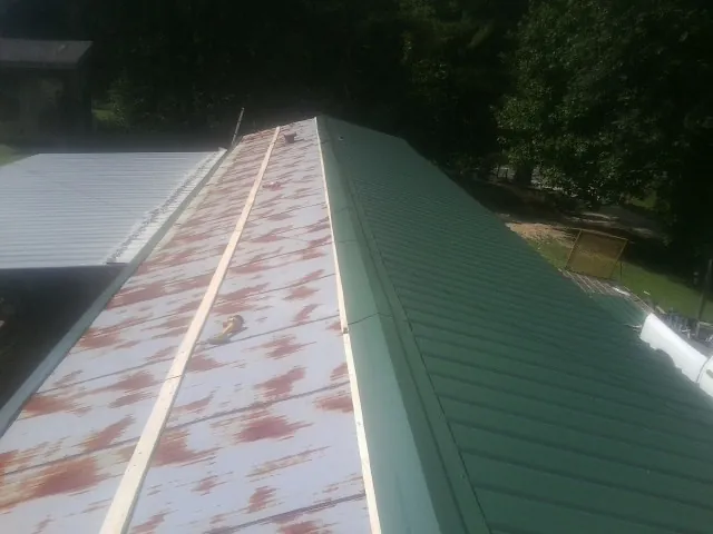 Old rusted panels beside newly installed green metal roofing — Wind Damage Roof Repair by Roofing Brothers in Teterboro