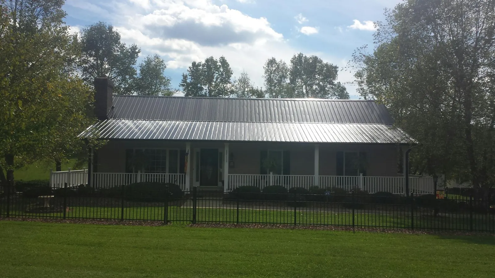 Gray metal roof on a brick ranch with a full width front porch — Gutter Guard Installation work by our crew in Teterboro