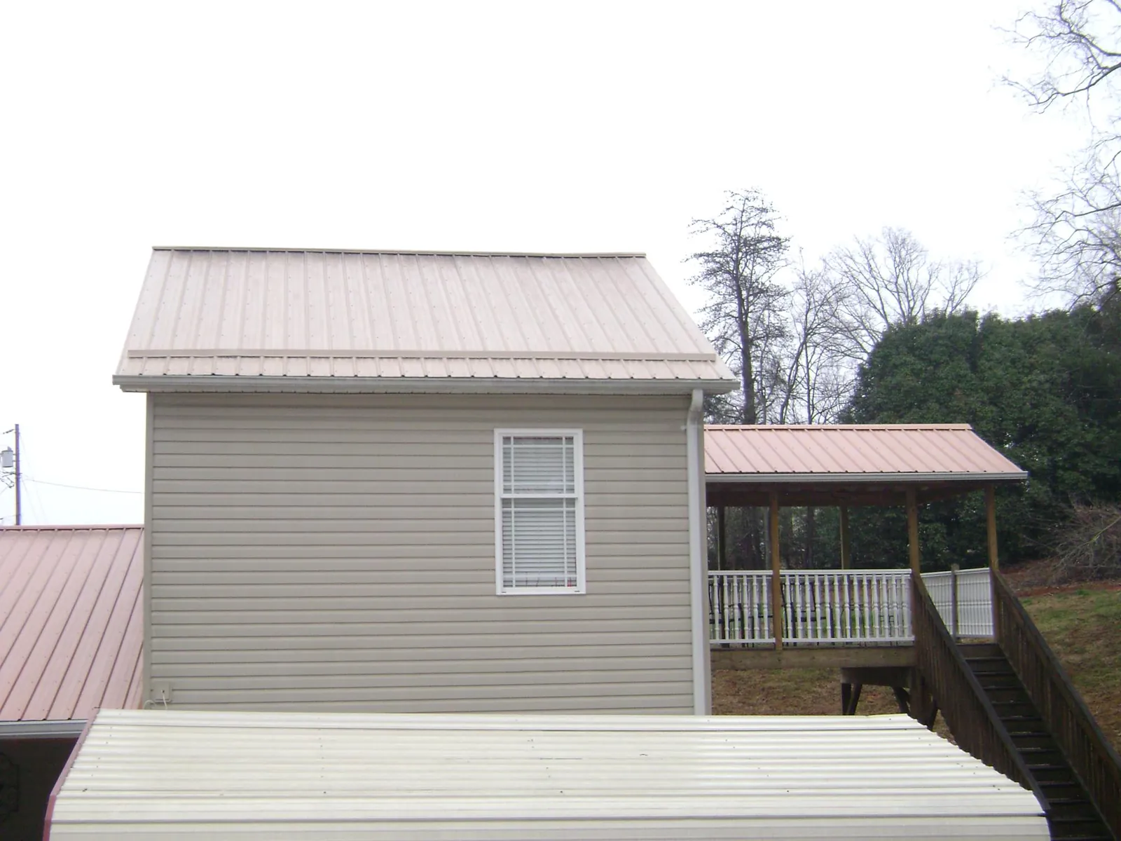 Tan metal roofs on a two story addition and attached porch, from a Roof Replacement job in Teterboro