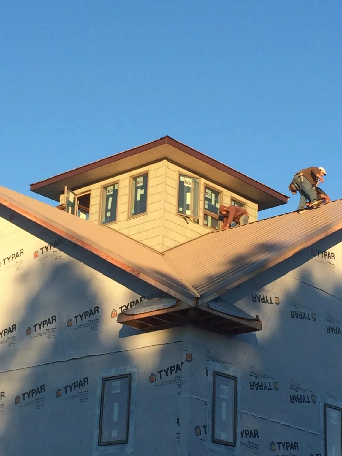 Roofers working around a rooftop cupola on a new metal roof at sunset — Roof Waterproofing in Teterboro by Roofing Brothers